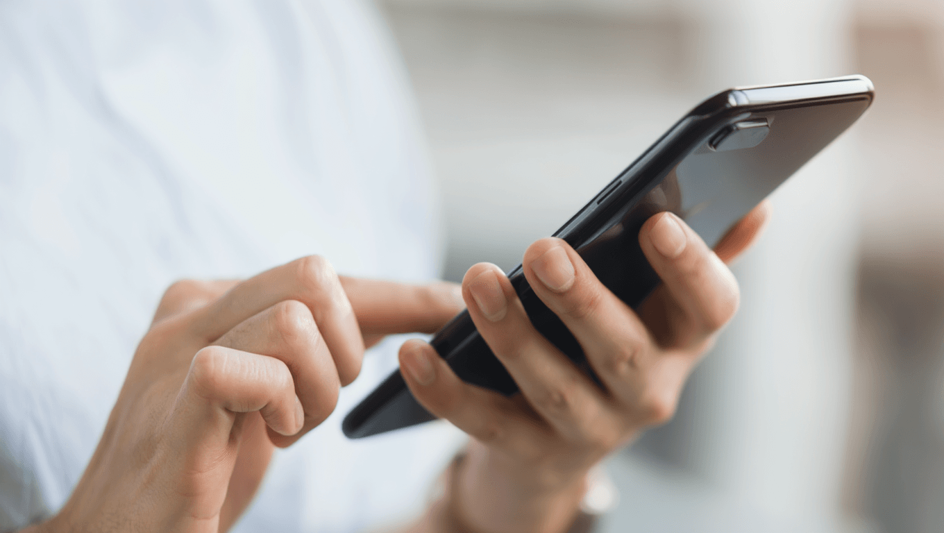 Mains tenant un téléphone noir avec écran tactile, doigt prêt à interagir avec l'appareil mobile en gros plan.