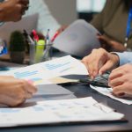 Équipe analysant ensemble des graphiques et données financières colorées autour d'une table de réunion, avec stylos et documents de travail.