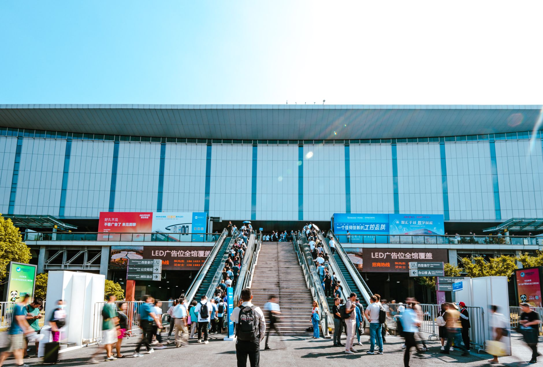 Des personnes entrant dans le centre d'exposition de Shanghai par un escalator extérieur pendant la journée.